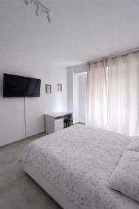 a white bedroom with a bed and a flat screen tv at Venera Rooms in Caltanissetta