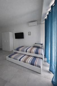 two beds in a room with a flat screen tv at Venera Rooms in Caltanissetta +1 photo