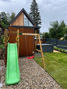 a playground with a green slide and a house at Lipno View Jenišov in Jenišov