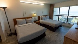a hotel room with two beds and a balcony at Beachfront 2BR 5th Floor Views Wakable SPI in South Padre Island