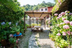 a garden with a wooden pergola and pink roses at Villetta Dina in Scoffera