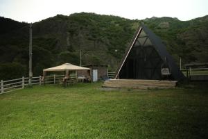 a tent with a table and an umbrella in a field at smile cottage in Borjomi