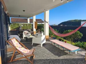 a patio with chairs and a hammock on a house at LAVA Açores Coliving in Ribeira Grande