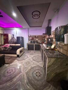 a living room with a couch and a kitchen with purple lights at Dixit's Villa! in Kānpur