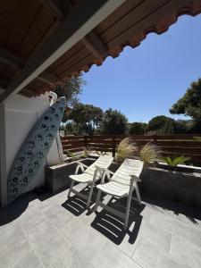 three chairs and a surfboard sitting on a patio at Sun & Sea in Sounio