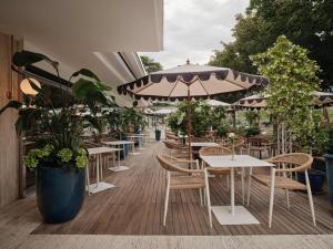 eine Terrasse mit Tischen, Stühlen und einem Sonnenschirm in der Unterkunft Hotel Aurora in Meran