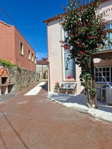 a building with a bench and a tree with red flowers at Casita relax Amariz Loureiro in Oya