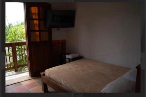 a bedroom with a bed and a balcony with a television at Hostal La Terraza Mirador in Jardin