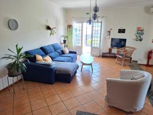 a living room with a blue couch and a chair at LAVA Açores Coliving in Ribeira Grande