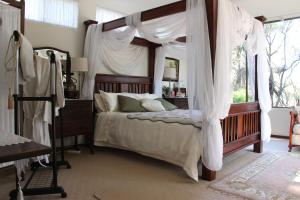 - une chambre avec un lit à baldaquin et des rideaux blancs dans l'établissement Whispering Pines Bed and Breakfast, à Collie