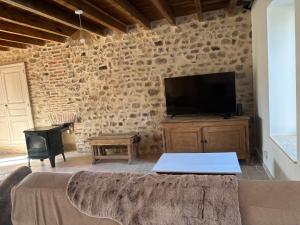 a living room with a tv and a stone wall at Gîte de Fumouse in Le Mayet-de-Montagne