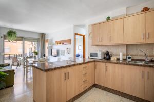 a kitchen with wooden cabinets and a dining room at Home2Book Sunny Terrace Apt, el Rincón de ManFe in Candelaria