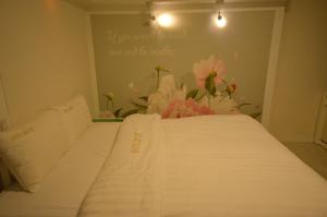 uma cama branca num quarto com flores na parede em Jeonju Cherevill Motel em Jeonju