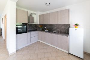 a kitchen with white cabinets and a tile floor at Apartma Luketovi in Vojščica +11 photos