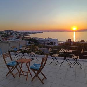 a group of chairs and tables on a balcony with the sunset at Antigone Salty Studio in Vathí