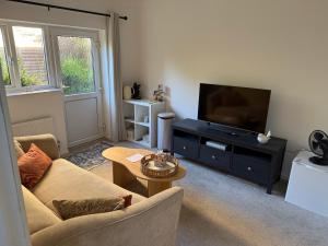 a living room with a couch and a flat screen tv at Penderels, Willersey in Broadway