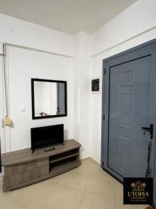 a living room with a television and a door at Utopia Apartment in Kallithea Halkidikis