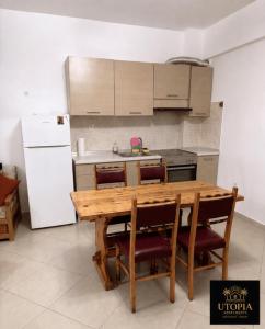 a kitchen with a wooden table and a white refrigerator at Utopia Apartment in Kallithea Halkidikis