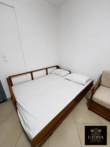 a bed with white sheets and a chair in a room at Utopia Apartment in Kallithea Halkidikis +1 photo