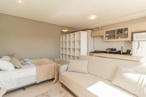 a bedroom with a bed and a couch and a kitchen at Loft Centralíssimo com Garagem in Pelotas