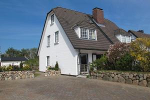 a white house with a black roof and a stone wall at Haus-Moewe-Jonathan-Wohnung-1 in Morsum