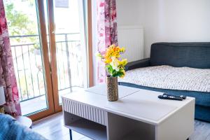 a living room with a table with a vase of flowers on it at Central Apartments Premium in Goleniów