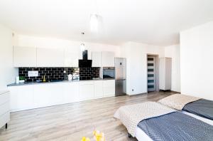 a kitchen with white cabinets and a bed in a room at Central Apartments Premium in Goleniów