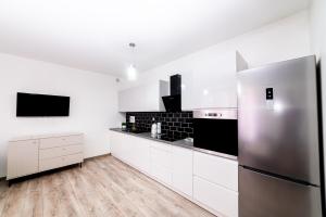 a kitchen with white cabinets and a stainless steel refrigerator at Central Apartments Premium in Goleniów +5 photos