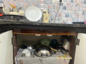 a shelf in a kitchen with dishes and a newspaper at Ujjain Sparsh Stays in Ujjain +10 photos