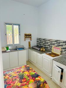 a kitchen with white cabinets and a fruit rug on the floor at Jenhani chokri in Kelibia