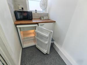 a small kitchen with a refrigerator and a microwave at Walnut Studio - Self Contained One-Bed Studio Flat in Oxford +10 photos