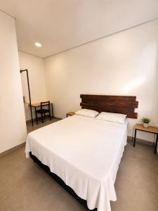a bedroom with a large white bed and a table at Mimos Hospedagem in São Paulo
