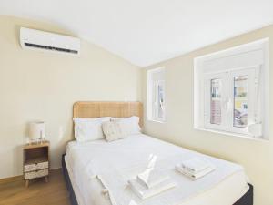 a white bedroom with a bed and two windows at 2BR Terrace with Tagus View - Air-Conditioned | By Airnest in Lisbon
