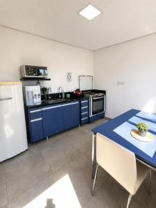 a kitchen with blue cabinets and a table and a refrigerator at Mimos Hospedagem in São Paulo