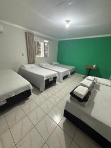 a bedroom with three beds and a green wall at hotel paiol mutum in Nova Mutum