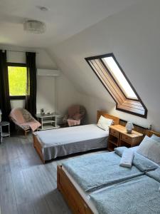 a attic bedroom with two beds and a skylight at Aniiza apartman in Örvényes