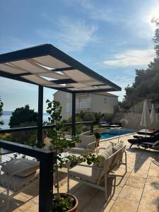 a patio with chairs and a pavilion next to a pool at Lavander Apartments Omiš in Duće