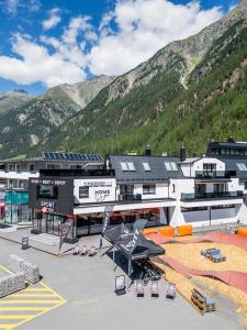 a large white building with mountains in the background at Home4You in Sölden