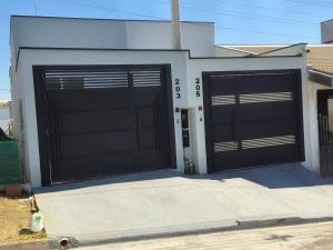 a garage with two black garage doors on a house at Casa 2 Quartos com Ar até 8 Pessoas Jd. Sabiás in Indaiatuba