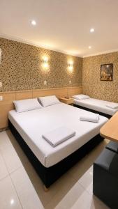 two beds in a room with two tables at Hotel Villa Rica in Rio de Janeiro +42 photos