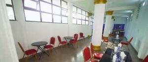 ein Zimmer mit roten Stühlen und Tischen und Fenstern in der Unterkunft Hotel Koliafo in Aného