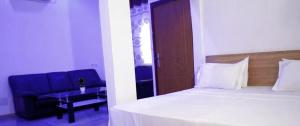 ein Schlafzimmer mit einem Bett und einem blauen Stuhl in der Unterkunft Hotel Koliafo in Aného