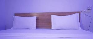 ein Bett mit zwei weißen Kissen und einem hölzernen Kopfteil in der Unterkunft Hotel Koliafo in Aného