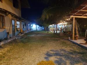 an alley at night with a palm tree and buildings at OCEANSURF hosteria in Mompiche