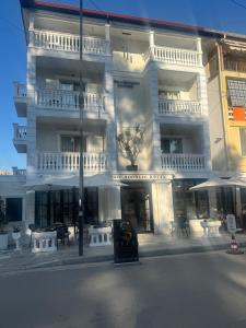 a large white building with tables in front of it at Hotel sefa brothers in Golem
