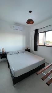 a bedroom with a large white bed with a window at Pousada Recanto dos Passaros in Aracati
