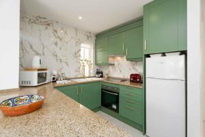 a green kitchen with green cabinets and a white refrigerator at Old Village & Prestige in Vilamoura