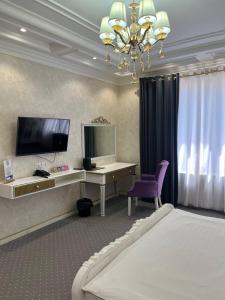 a bedroom with a bed and a desk and a tv at Suleyman House Premium in Bukhara