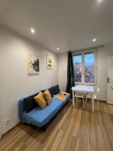 a living room with a blue couch and a table at Chemin de fer adorable appartement in Gagny