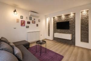 a living room with a couch and a tv on a brick wall at App Aurum in Brtonigla